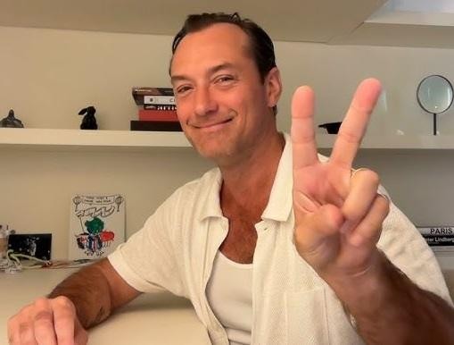 Jude Law na scenie, w dynamicznej pozie podczas występu teatralnego, ukazujący jego sceniczną ekspresję.