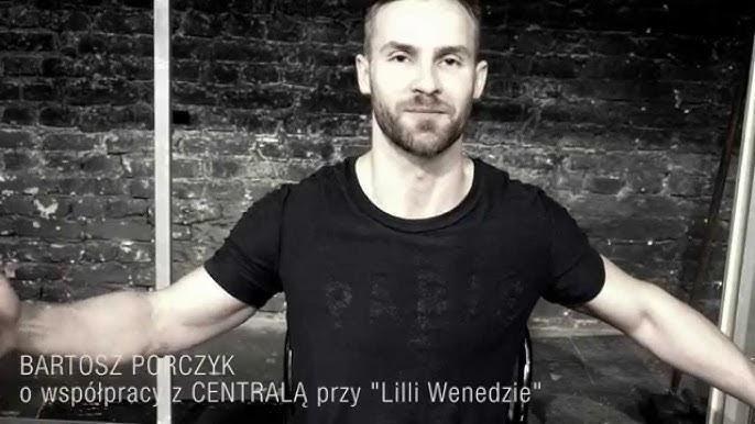 Bartosz Porczyk na scenie teatralnej podczas występu, oświetlony dramatycznym światłem reflektorów.