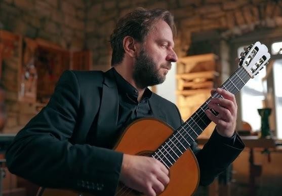 Zbliżenie na dłonie Marcina Dylli grające na gitarze klasycznej, podkreślające precyzję i maestrię wykonania.
